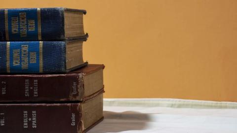 Stoh vintage anglicko-španělských slovníků na stole, ilustrace učení angličtiny od nuly