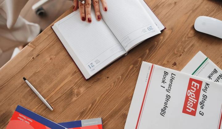 Otevřený sešit a učebnice angličtiny na stole · Foto: Polina Tankilevitch / Pexels Sešit a učebnice angličtiny na dřevěném stole jako plán studia od nuly