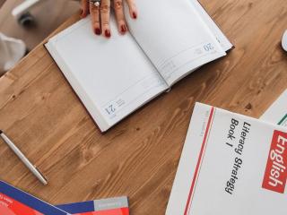 Sešit a učebnice angličtiny na dřevěném stole jako plán studia od nuly